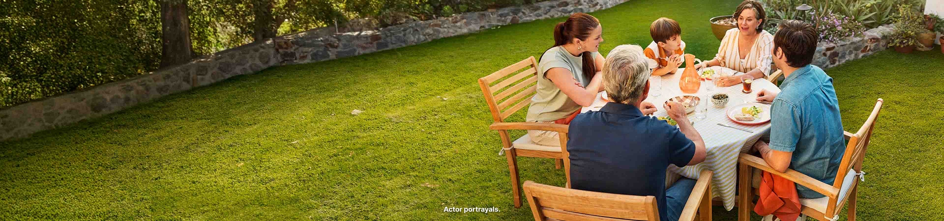 Family eating at table on lawn. Actor portrayals.